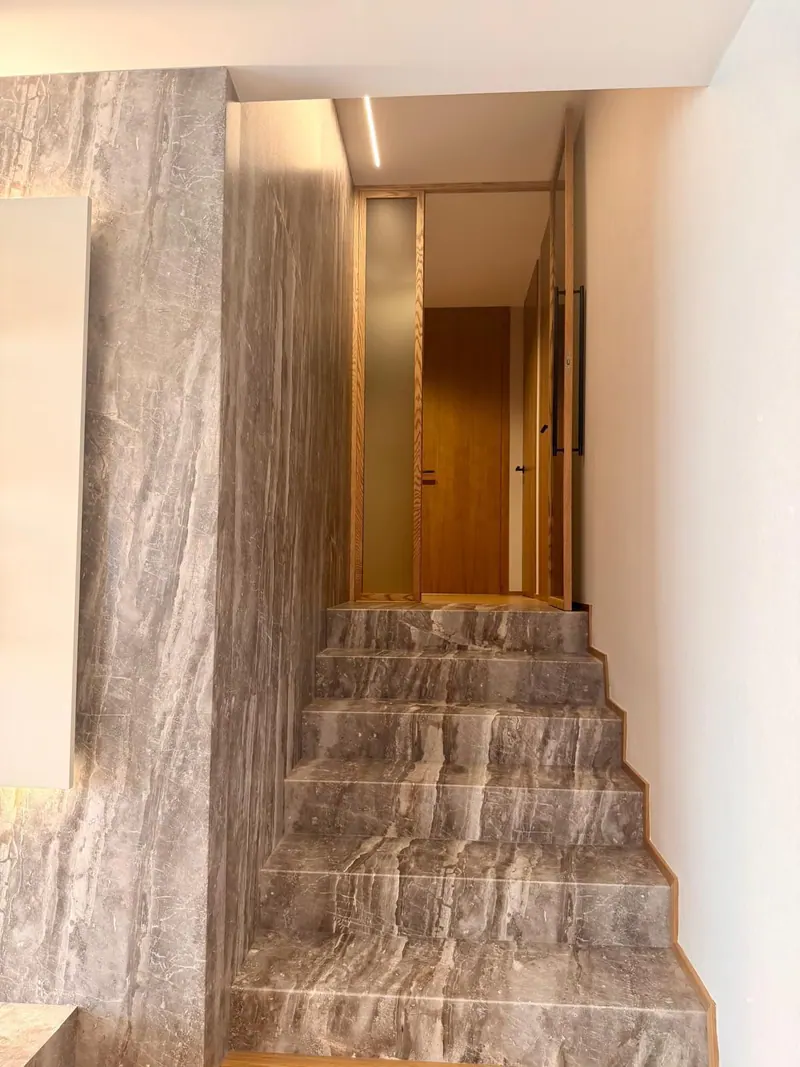 Escalera cuyos peldaños y paredes están revestidos con paneles de efecto piedra gris con vetas